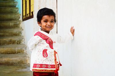 Smiling baby boy standing by wall