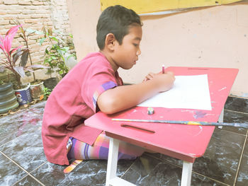 Side view of boy sitting on table