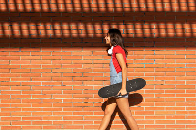 Side view of woman standing against brick wall