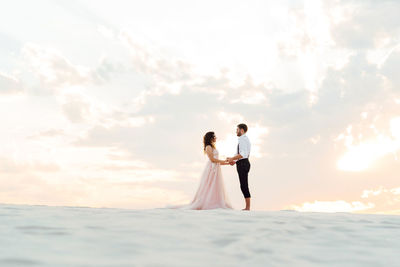 Couple standing in sea against sky