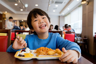 Portrait of boy eating food in restaurant