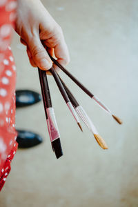 Cropped image of hand holding paintbrushes