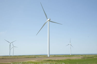 Wind turbines on field against clear sky