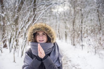 Girl standing snow covered land against trees