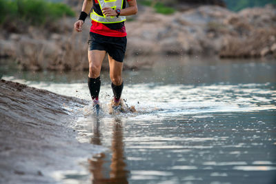 Low section of man running on wet beach