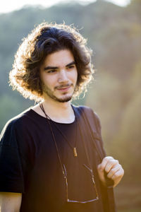 Man looking away while standing outdoors in sunny day