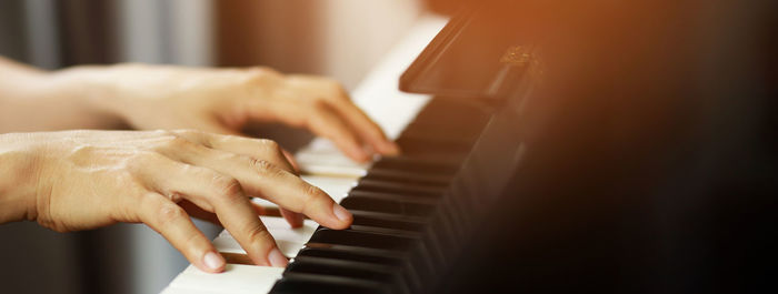 Cropped hand of woman playing piano