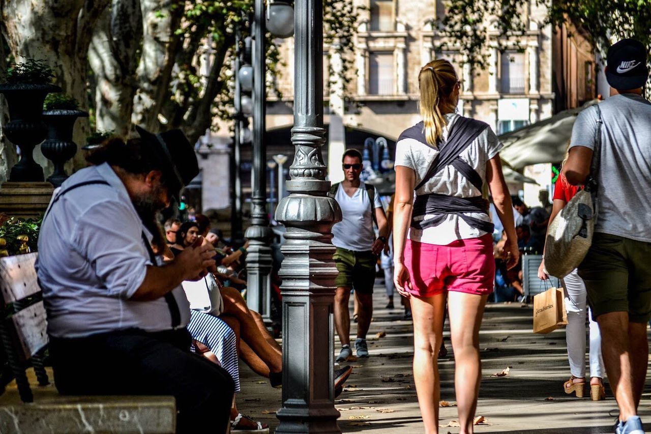 REAR VIEW OF PEOPLE WALKING ON STREET AMIDST BUILDINGS