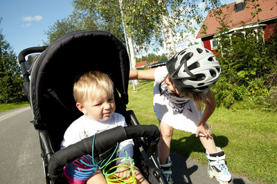 Girl looking at brother while sitting in baby stroller