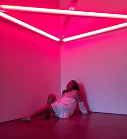 Full length of woman in illuminated pink room