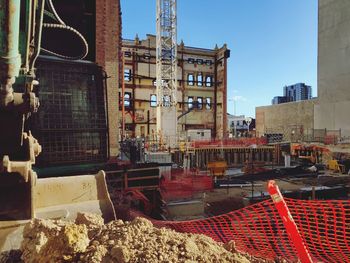 Construction site by buildings in city against sky