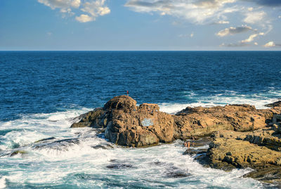 Scenic view of rocks in sea against sky