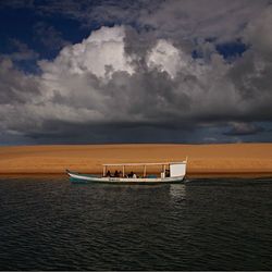 Boats in sea against cloudy sky