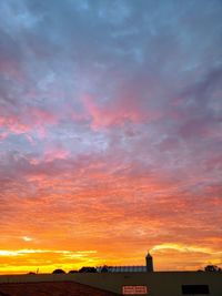 Silhouette buildings against dramatic sky during sunset