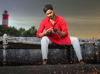 Full length of young man sitting outdoors