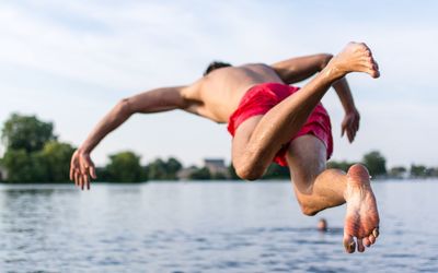 Midsection of man jumping against sky