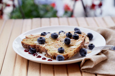 Sweet wholegrain sandwiches with fresh blueberries, almond flakes and agave syrup on a plate outside