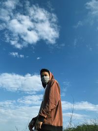 Low angle view of man wearing mask against sky