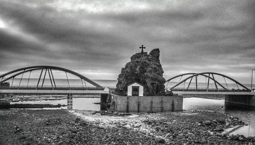 Bridge over river against cloudy sky