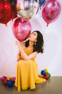 Young woman holding balloons against white background