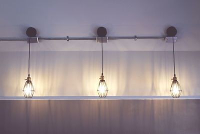 Low angle view of illuminated light bulbs hanging from ceiling