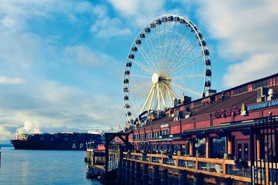 Ferris wheel in city against cloudy sky