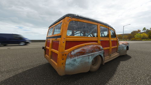 View of yellow car on road against cloudy sky