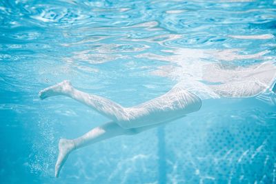 Low section of person swimming in pool