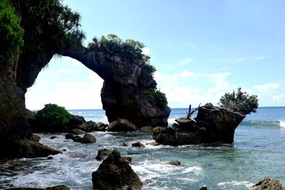 Rock formation by sea against sky