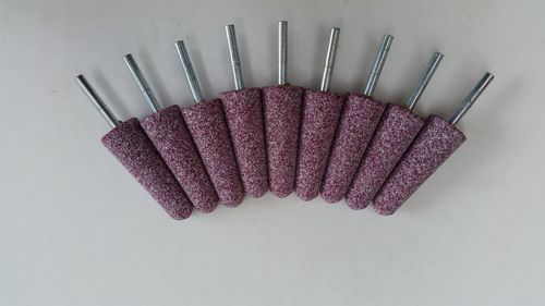 Directly above view of magenta grinding stone drill bits on white background