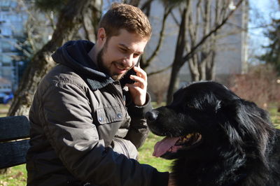 Smiling man looking at dog while talking on phone