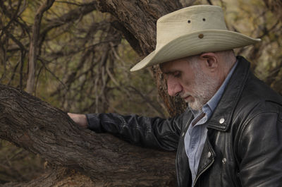 Portrait of adult man in cowboy hat against tree