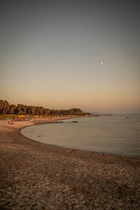 Scenic view of beach against clear sky during sunset