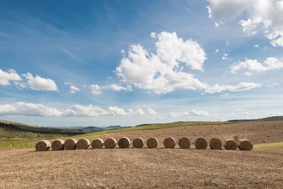 Hay bales on field against sky