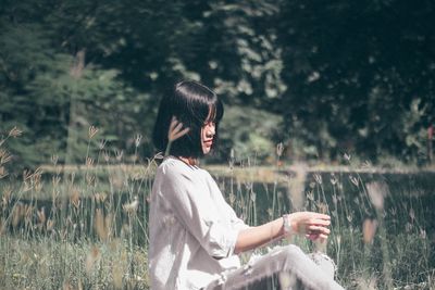 Side view of young woman sitting on land