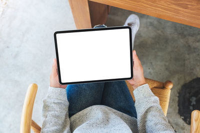 Low section of woman using digital tablet on table