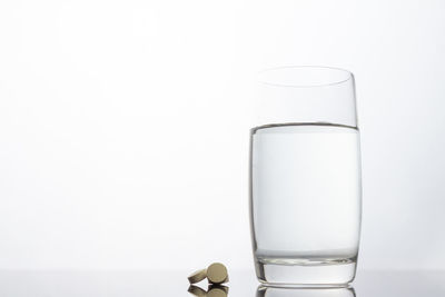 Close-up of water glass on table against white background
