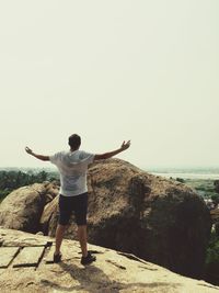 Rear view of man standing on rock against sea