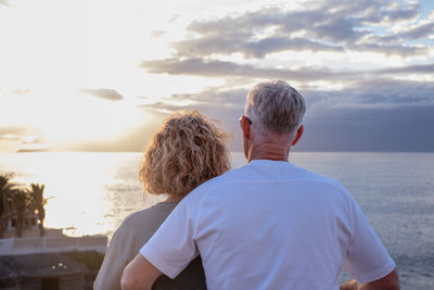 Rear view of couple standing against sea