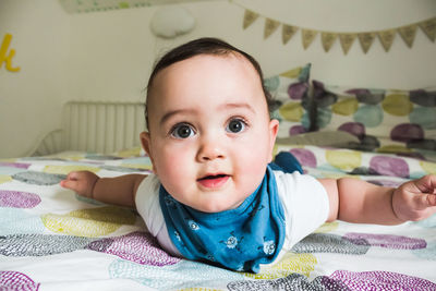 Portrait of cute baby lying on bed at home