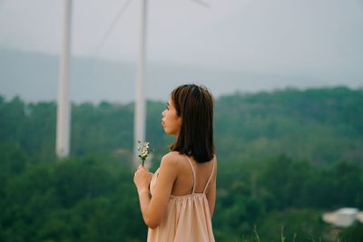 Young woman standing against plants