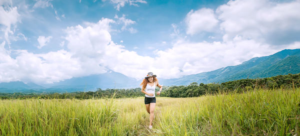Full length of woman standing on field against sky