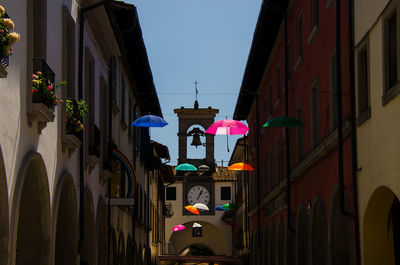 Multi colored umbrellas hanging amidst buildings