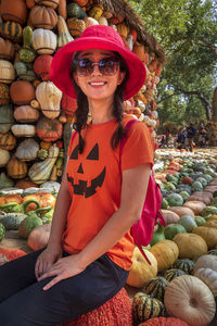 Portrait of smiling woman sitting on pumpkins