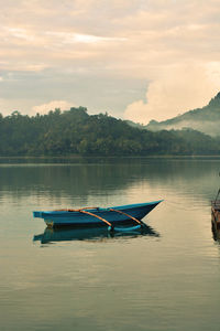 Boat moored in lake against sky