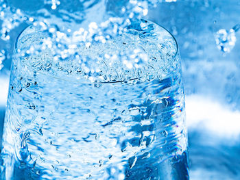 Close-up of wet glass against blue water