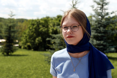 Portrait of young woman standing against trees