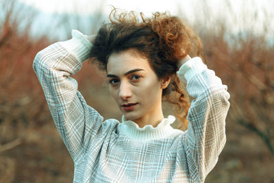 Portrait of young woman standing against plants