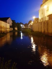 River by illuminated buildings against sky at night