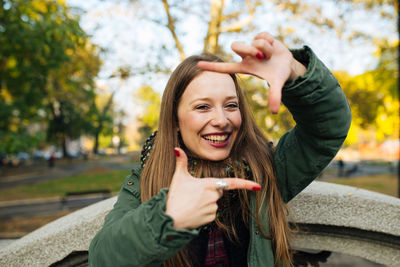 Portrait of smiling young woman gesturing in park